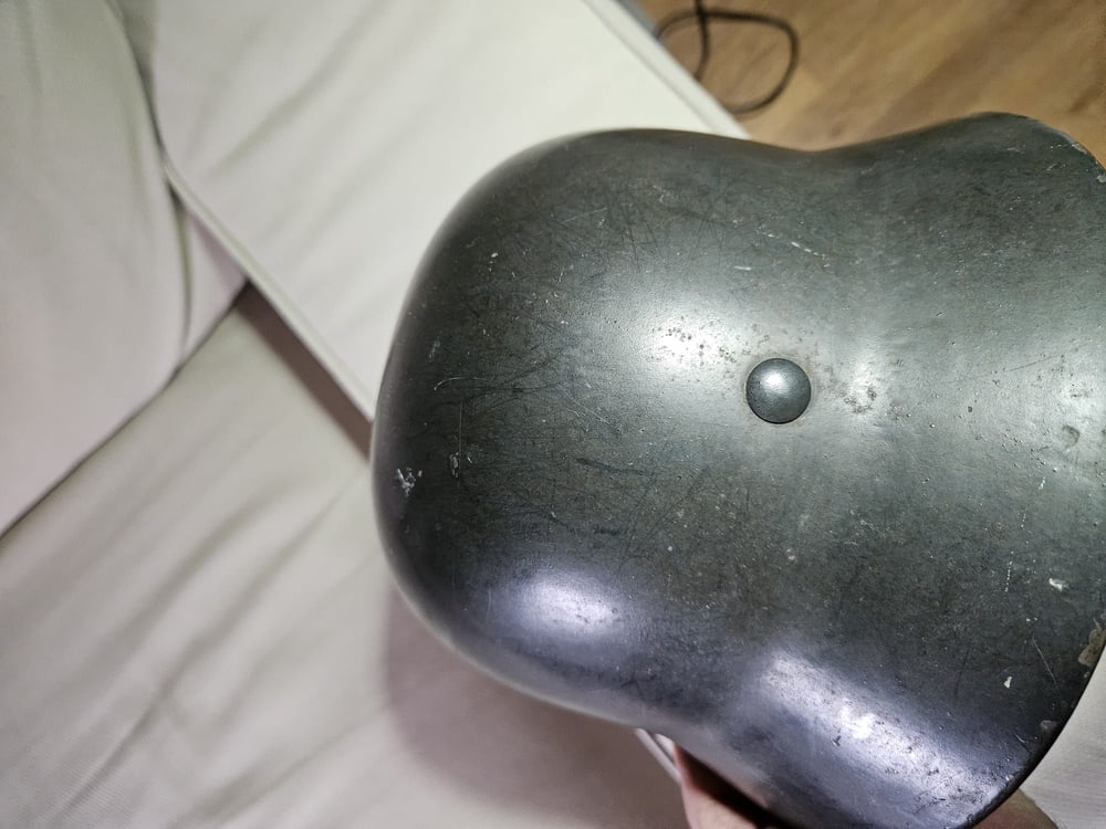 El mismo casco a contraluz: la curva del acero y el remache lateral.