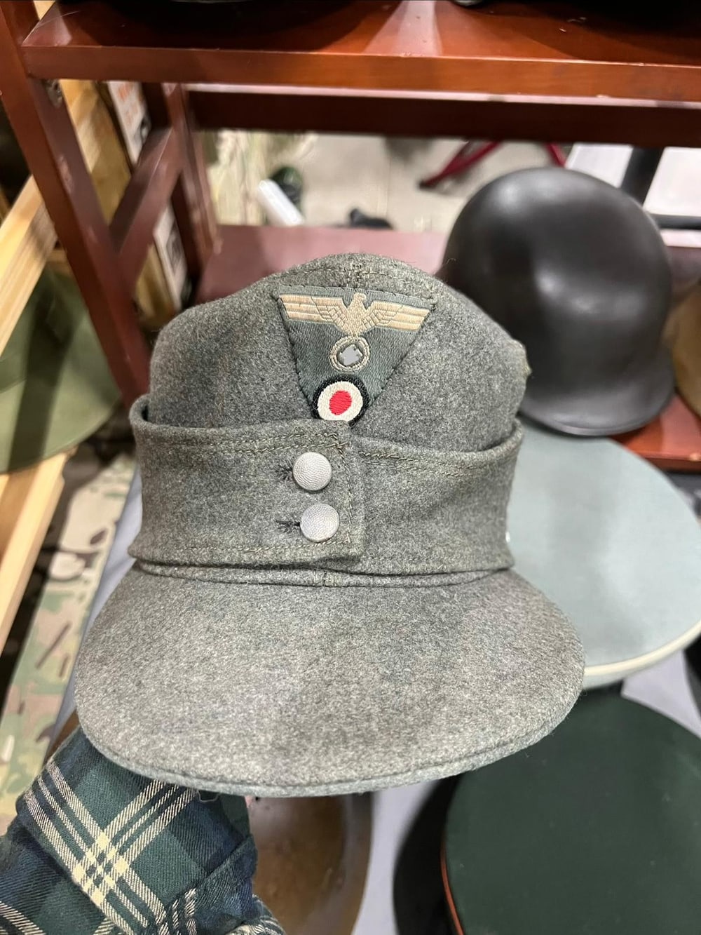 Gorra M43 de la Wehrmacht, con la escarapela y el águila en su triángulo. El símbolo va tapado (§ 86a StGB).