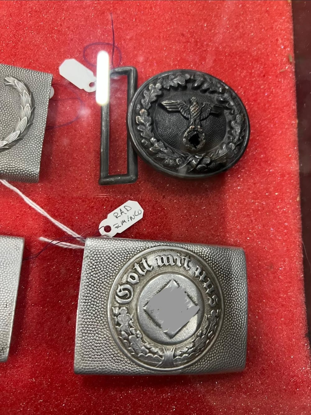 Hebillas de cinturón de la Wehrmacht: la de tropa con el lema «Gott mit uns» y la redonda de oficial con corona de roble. Símbolos tapados (§ 86a StGB).