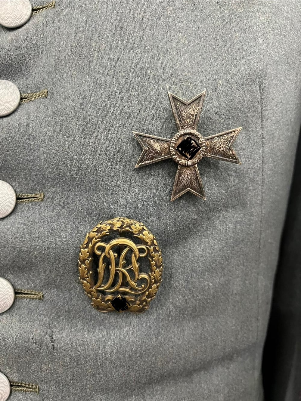 Cruz al Mérito de Guerra de 1.ª clase sin espadas y distintivo deportivo del Reich (DRL), prendidos en la guerrera. Símbolos tapados (§ 86a StGB).